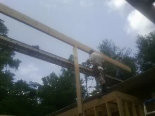 Carpenter setting a ridge beam over a new addition frame — Ice Dam Removal by Roofing Brothers in Elbridge