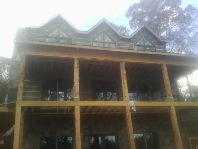 Dormers and porch framing on a large log home under construction — Roof Coating work by our crew in Elbridge